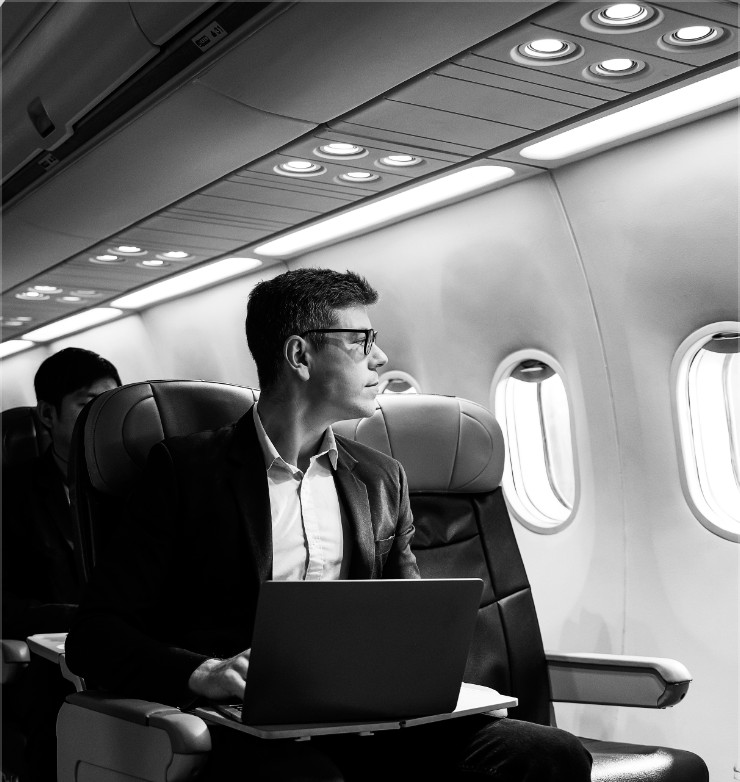 Man working on laptop looking out airplane window